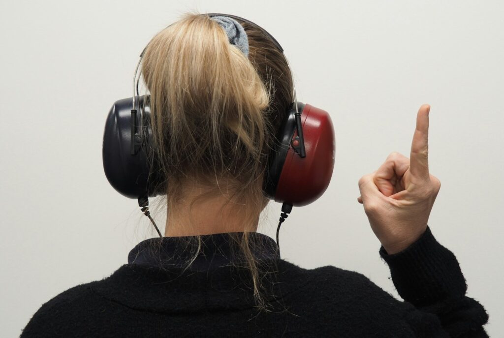 Woman wearing headphones pointing to the side during a hearing test