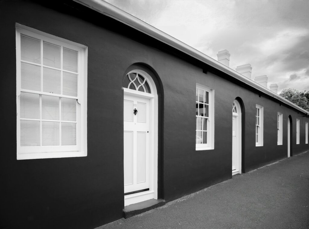 Row of dark buildings with white windows and doors, relevant to period timber windows