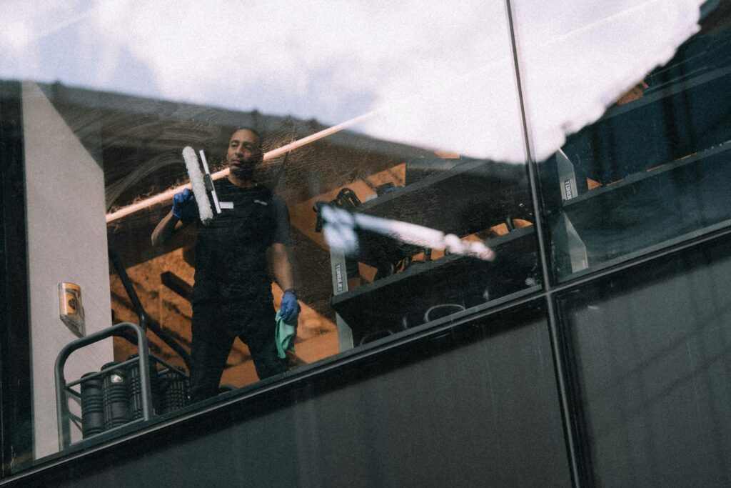 Man cleaning windows on a tall building, where professional safety standards matter